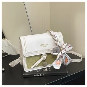 Detail of color-block flap bag with silk scarf accessory and gold fashion lettering
