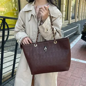 Sac cabas marron foncé avec motifs tête de mort gaufrés et détails tête de mort en métal