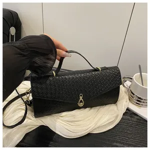 Détail d'un sac à main noir tressé avec un fermoir métallique doré en forme d'infini