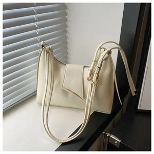 Detail of cream leather shoulder bag with gold metal clasp and adjustable strap
