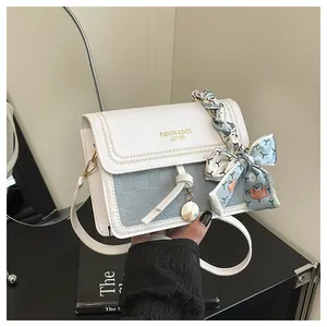 Detail of square crossbody bag with blue texture, scarf handle and metal charm