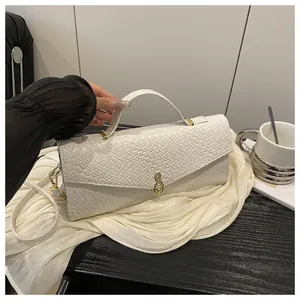 Détail de la texture croco blanc et du fermoir doré en forme d'infini sur le sac à main