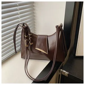 Detail view of dark brown glossy leather saddle bag with golden triangle hardware