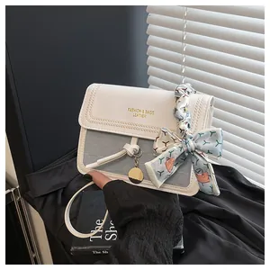 Detail of grey-blue woven texture crossbody bag with silk scarf and gold pendant