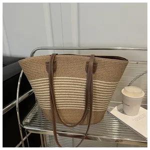 Detail of striped woven straw tote bag with brown faux leather straps on a metal trolley