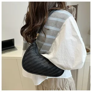 Dettaglio della borsa a mezzaluna intrecciata in pelle nera indossata da una modella