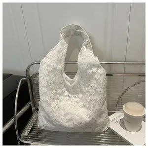 Detail shot of white floral embroidery on premium lace tote bag with yellow accents