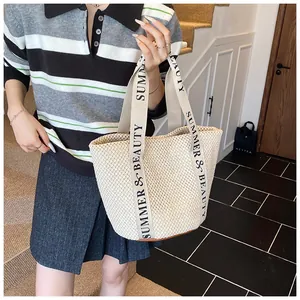 Gros plan d'un sac cabas en paille avec texte SUMMER & BEAUTY sur les poignées