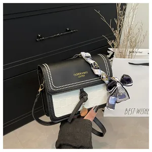 Detail of contrast square bag with bow silk scarf handle and golden brand lettering