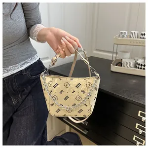 Détail d'un sac seau beige avec motifs ours, chaîne en métal et texture grainée