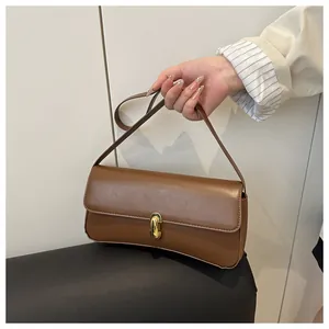 Close-up of a brown leather shoulder bag featuring a golden oval metal lock and strap