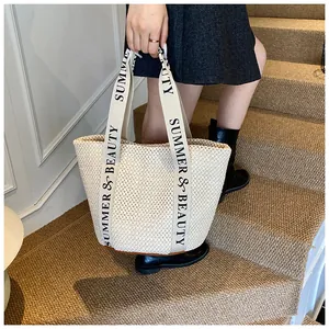 Détail du sac cabas en paille crème avec texte Summer & Beauty sur les anses en extérieur