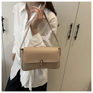 Detailed view of beige faux leather shoulder bag with gold clasp shown on a model