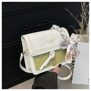 Detail of green checkerboard patterned crossbody bag with silk scarf handle and gold pendant