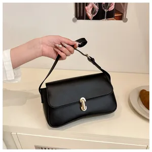 Detail of a black leather shoulder bag with a gold metal lock and adjustable strap