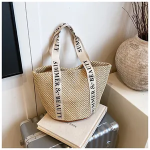 Détail du sac cabas en paille avec anses 'SUMMER & BEAUTY' sur une valise argentée
