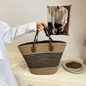 Khaki straw tote bag with black stripes and brown leather handles for summer beach style