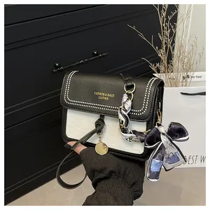 Detailed close-up of a contrast leather crossbody bag with silk scarf and chain strap