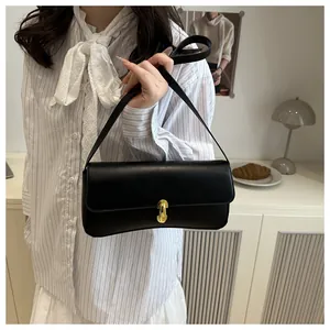 Detail of minimalist black leather shoulder bag with a stylish gold horseshoe buckle