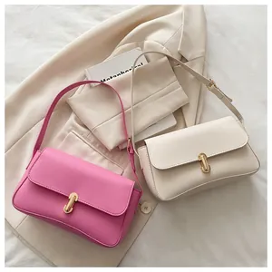 Detailed view of the U-shaped gold metal buckle on pink and beige leather handbags