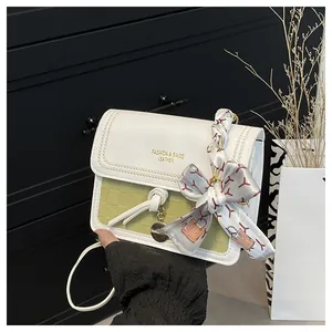 Close-up of green checkered crossbody bag with white leather flap and silk scarf handle