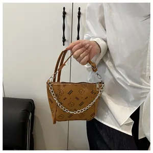 Détail d'un sac seau marron avec chaîne argentée et motif d'ours mignon imprimé