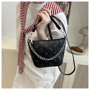 Détail du sac seau noir avec imprimé ours et chaîne métallique sur une table blanche