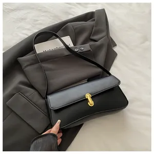 Close-up of minimalist black leather shoulder bag with a polished golden metal clasp