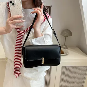 Elegant black faux leather baguette bag with gold buckle on white minimalist background