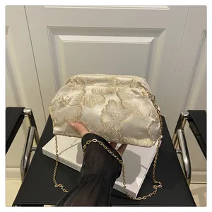 Detail of elegant gold champagne satin evening bag with floral embroidery and gold chain