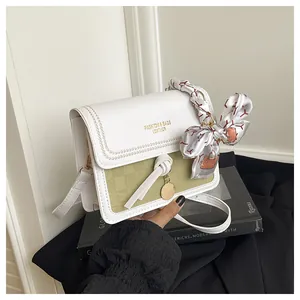 Close-up of woven texture small square bag with silk scarf handle and gold hardware
