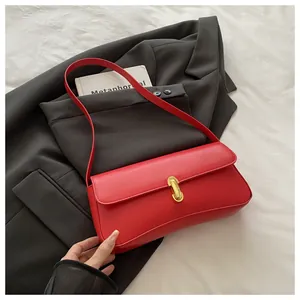 Detailed view of red minimalist baguette bag with gold buckle on a black blazer