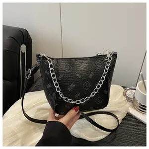 Détail du sac seau en cuir noir texturé avec motif d'ours et chaîne argentée