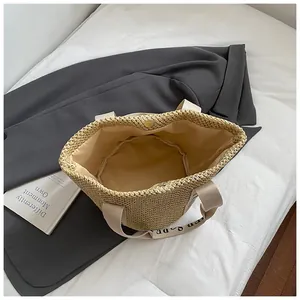 Détail du sac en paille tressée montrant la doublure en tissu et le fermoir magnétique