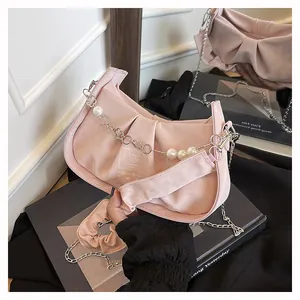 Detail of pink pleated bag featuring silver chain with white pearls and metal floral charms