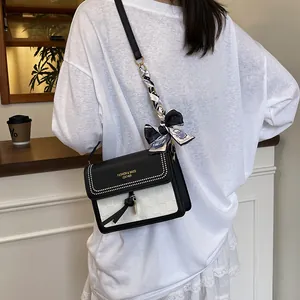 Chic black and white crossbody bag with woven texture and silk scarf handle detail