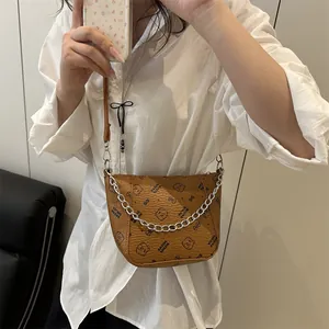 Sac seau marron avec imprimé ours et chaîne porté par un mannequin en chemise