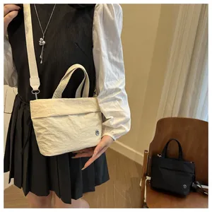 Detail of a pleated mini bucket bag with adjustable wide strap in cream and black