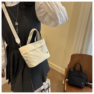 Close-up of pleated beige bucket bag with wide strap and metallic logo detail
