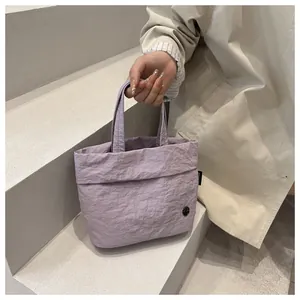 Detail of lavender wrinkled nylon tote bag with black logo and handle on simple background