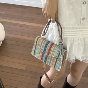 Detailed close-up of a colorful woven handbag with striped pattern and knot handle