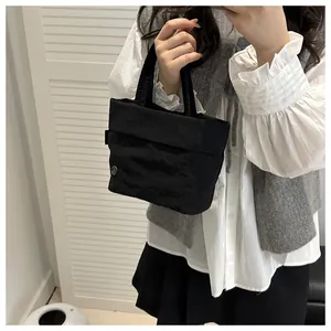Mirror selfie showing a black textured nylon bucket bag with a circular metal logo
