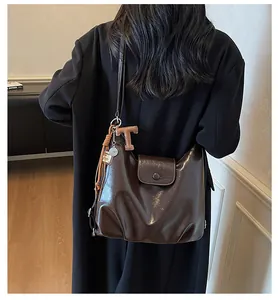 Détail d'un sac hobo en cuir huilé marron foncé avec pendentif en T et plaque en métal