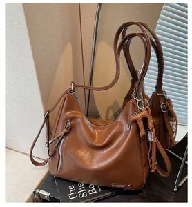 Détail d'un sac à bandoulière en cuir marron avec finition vintage et zips métalliques