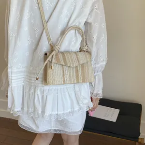 Vertical striped beige woven tote bag styled with a white dress in a minimal home setting