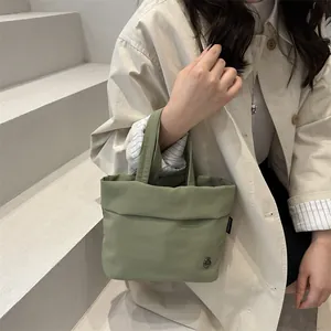 Minimalist light green bucket bag with side label and metal button detail