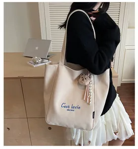 Détail du sac cabas en toile beige avec broderie bleue et breloque ours en peluche