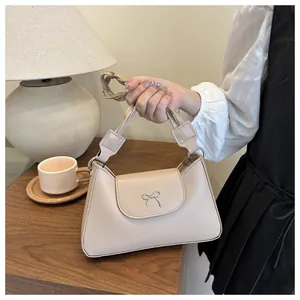 Dettaglio borsa beige con fibbia a fiocco argento e manico intrecciato a torsione