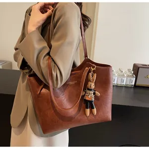 Détail d'un sac cabas en similicuir marron avec logo et pendentif de lapin mignon
