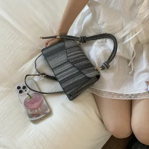 Detail of woven texture on grey and black striped crossbody bag with rope handle